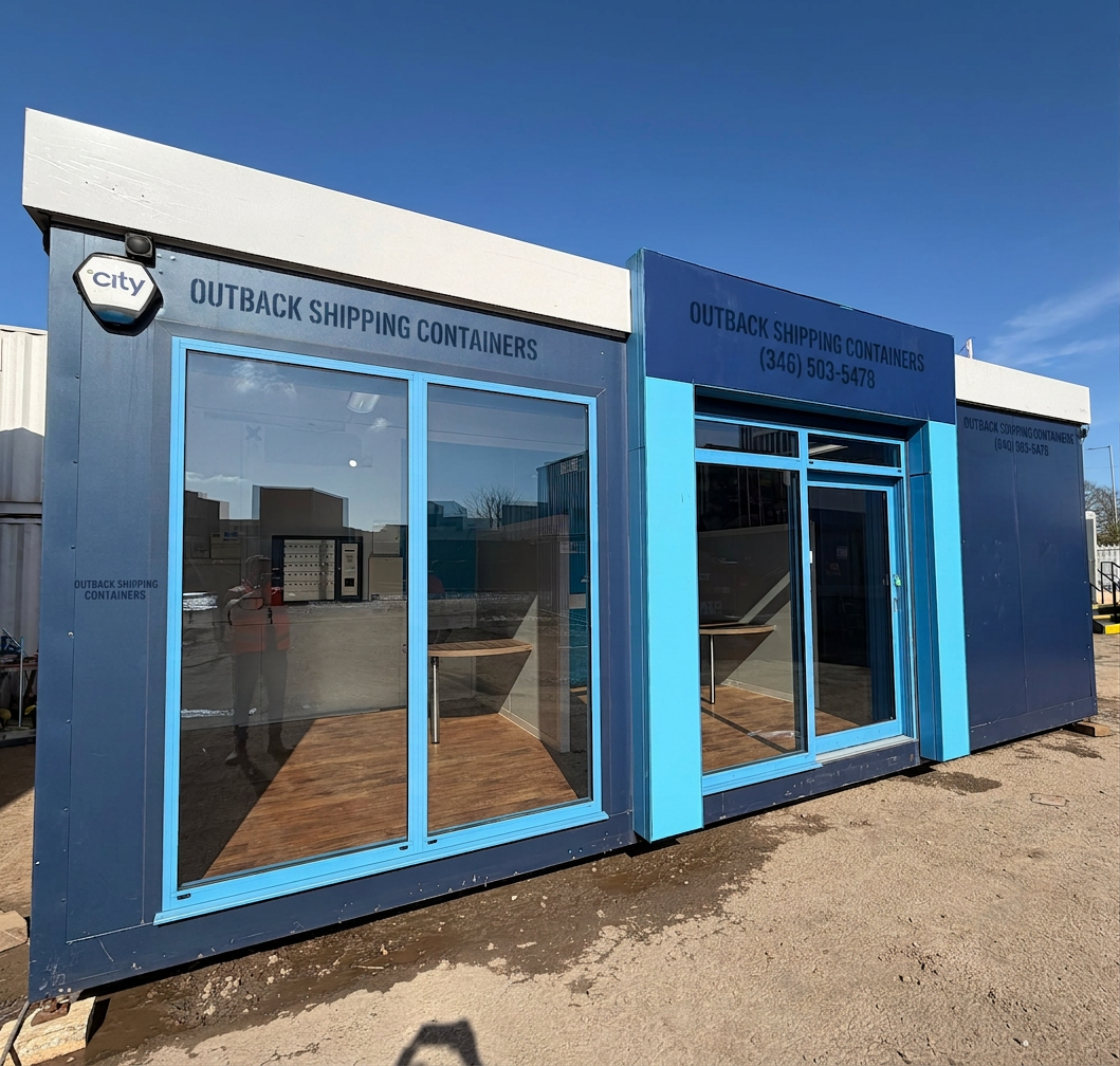 Refurbished 26x12ft portable marketing suite with blue panels and large glass windows under a clear sky