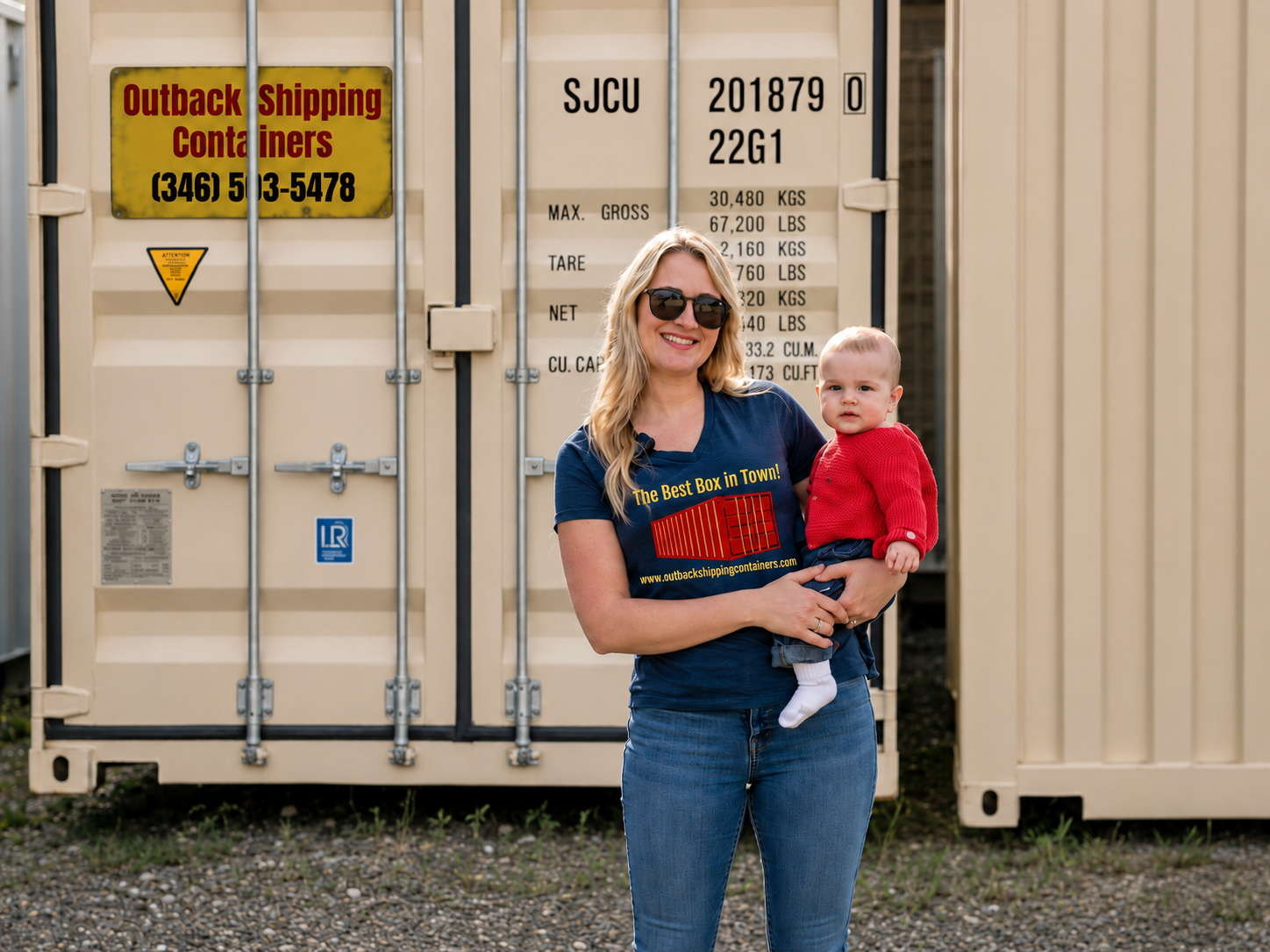 Outback Shipping Containers team member holding her child in front of a branded shipping container in Sheridan, WY