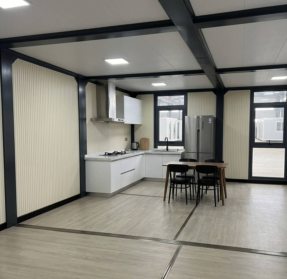 Open-plan ground floor of the 4 bedroom luxury container home villa showing the kitchen run, stainless refrigerator and dining table with the living area open to the left