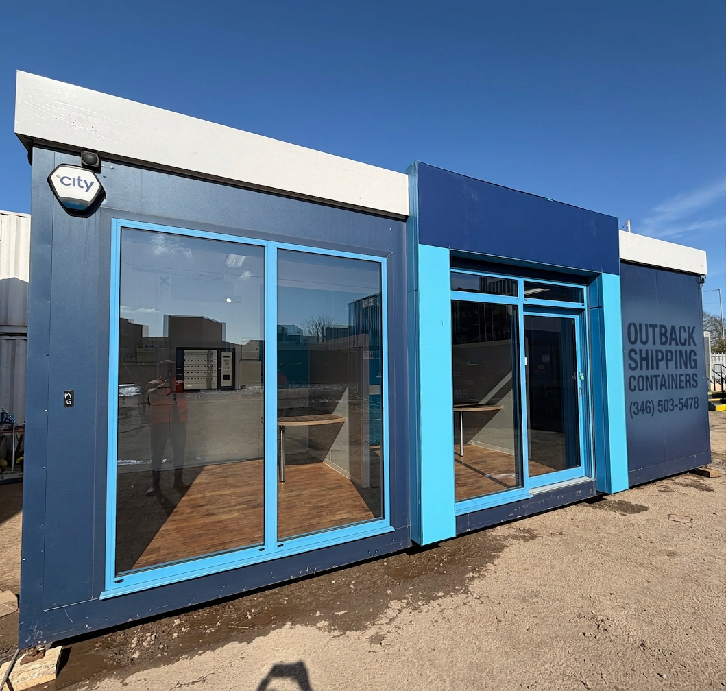 26x12ft marketing suite sales pod with blue facade large glass windows and wood style flooring under a clear blue sky