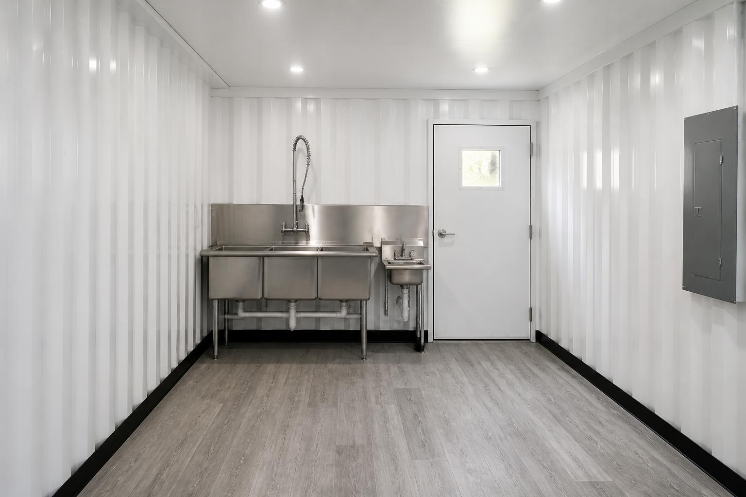 Back-of-house prep bay with a three compartment stainless sink and separate hand wash basin