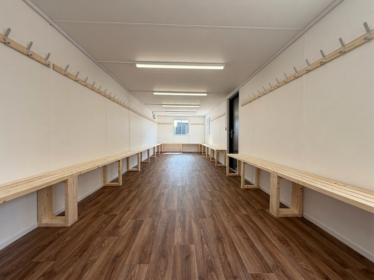 Interior view of a 32x10ft container drying room with wooden benches and coat hooks on white walls