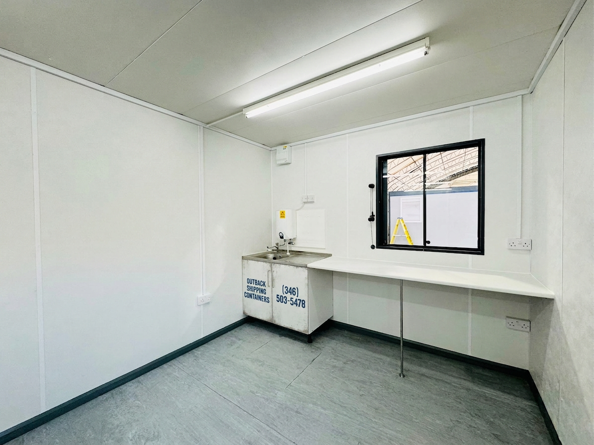 Refurbished 32x10ft container changing room interior with white walls, a sink vanity, and long work counter