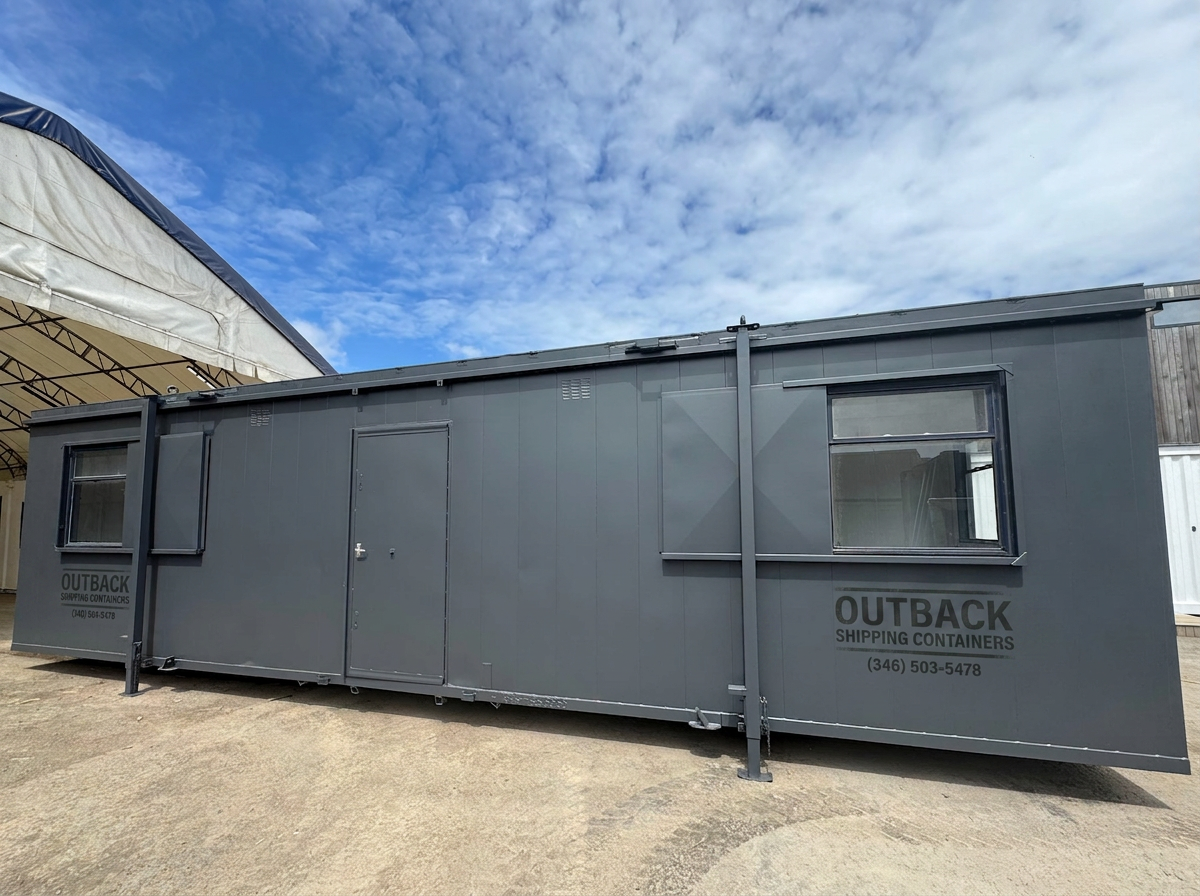 Refurbished 32x10 ft dark grey anti-vandal portable cabin with steel shutters and central door under a bright sky